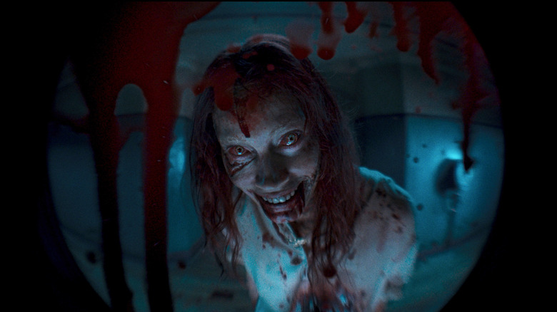 Alyssa Sutherland as Ellie looking through the bloody peephole in Evil Dead Rise