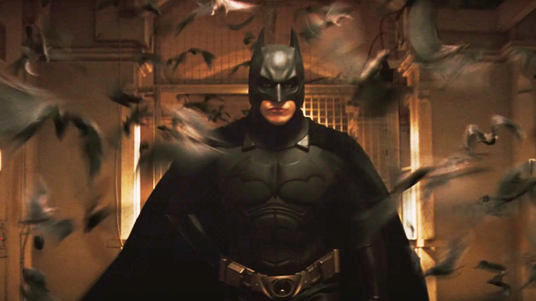 Batman running surrounded by a swam of bats in Batman Begins