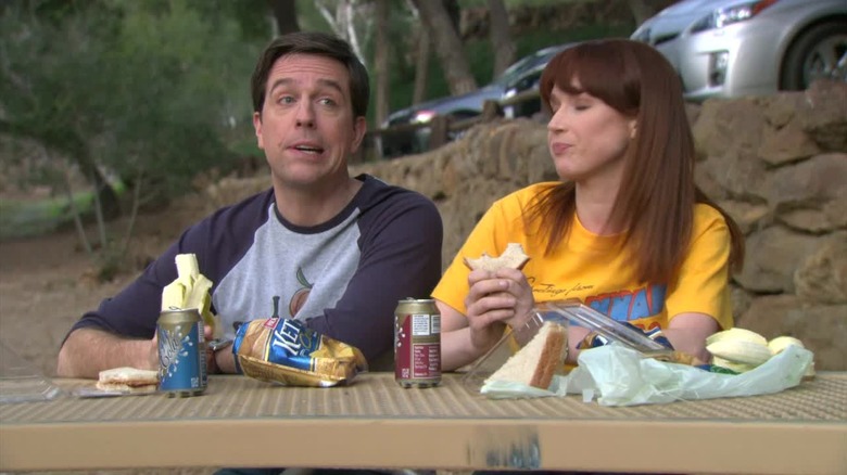 Andy and Erin sit on a picnic table in the office