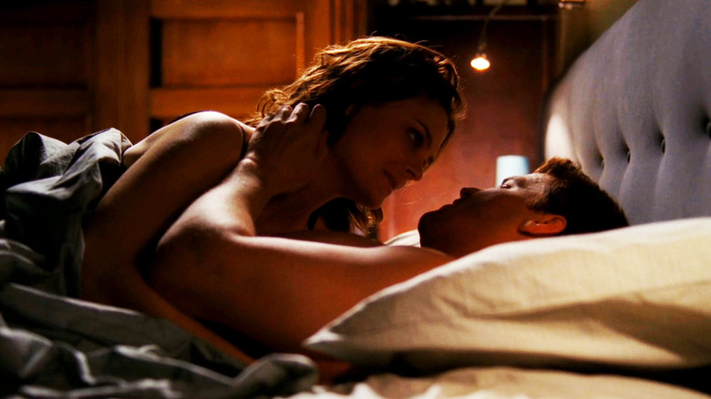 Emily Deschanel's Temperance Brennan lies on top of David Boreanez's Seeley Booth in bed in Bones