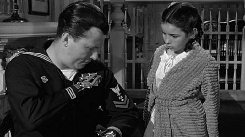 Harold Russell as Homer in The Best Years of Our Lives, fixing his uniform with his metal hooks while Marlene Aames' Luella looks on