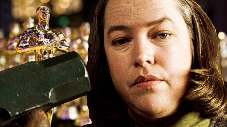 Annie in Misery holding a sledgehammer, with a backdrop of Oscars statuettes