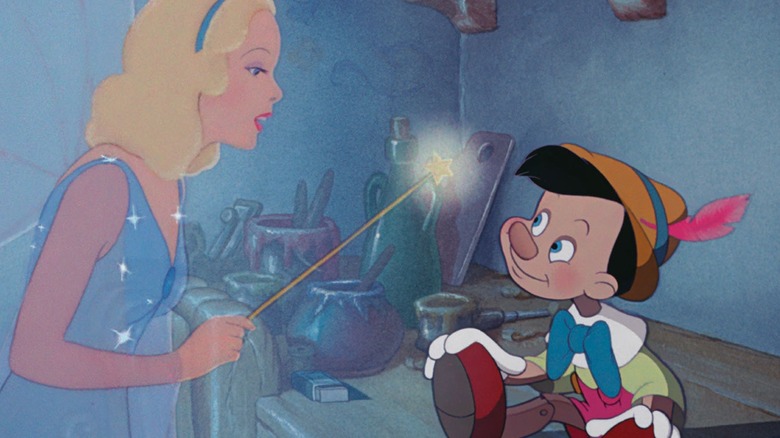 Pinocchio sits at a table in the Heppet's workshop, looking at the blue fairy, in Pinocchio