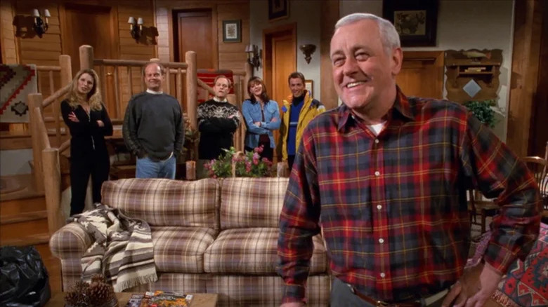 Martin Crane smiling in a lodge, in front of the cast of Frasier