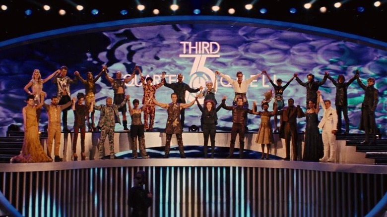 The 75th Hunger Games' tributes hold hands atop a stage