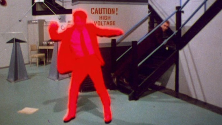 Murray Hamilton's Lewis glows red in a room with a sign that reads "Caution! High Voltage" in The Invaders. Roy Thinnes' David Vincent is barely visible in the background