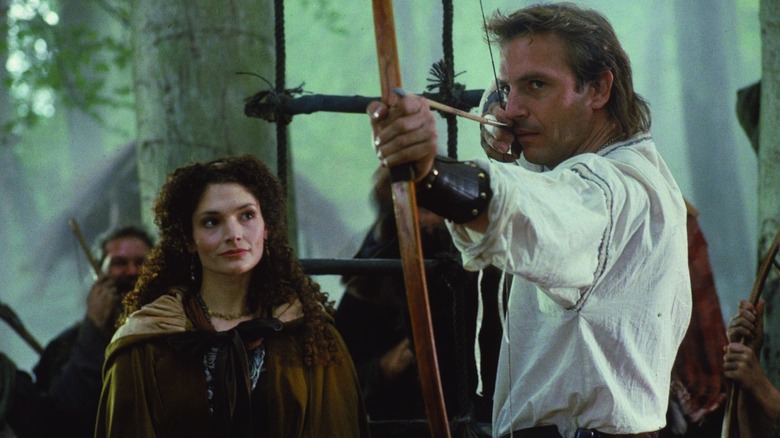 Mary Elizabeth Mastrantonio as Lady Marian watches Kevin Costner as Robin fire a shot in Robin Hood: Prince of Thieves