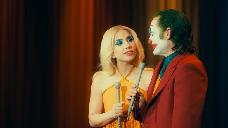 Lady Gaga and Joaquin Phoenix in character, holding old-timey microphones