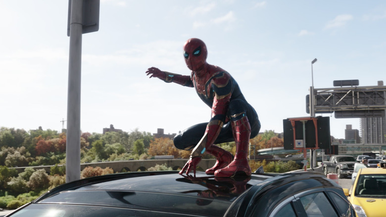 Spider-Man se sienta encima de un auto en Spider-Man: No Way Home