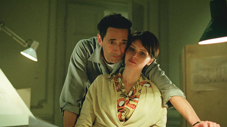 Adrien Brody as Laszlo Toth gazes over the shoulder of Felicity Jones as Erzsébet Toth in The Brutalist