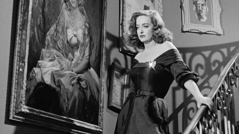 Margo Channing, looking peeved, walking down a staircase in All About Eve