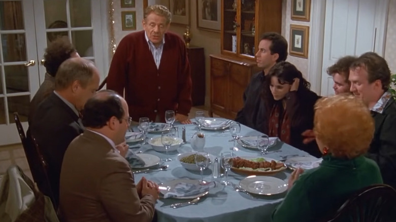 Para pemeran Seinfeld berkumpul di sekitar meja makan dengan Jerry Stiller sebagai Frank Costanza di Seinfeld