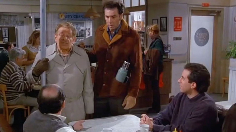 Jerry Stiller as Frank Costanza, Michael Richardson as Cosmo Kramer, and Jerry Seinfeld as Jerry Seinfeld gathered around a table on Seinfeld