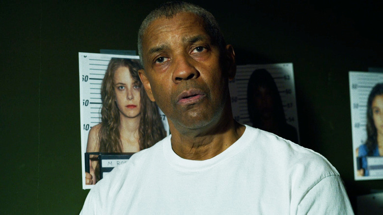 Denzel Washington's Joe Deke Deacon Looks surprised as he stands against a wall with photos of missing women in The Little Things