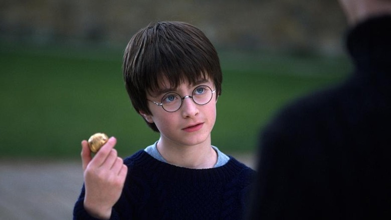 Harry holding a Golden Snitch with extremely blue eyes in Harry Potter and the Sorcerer's Stone