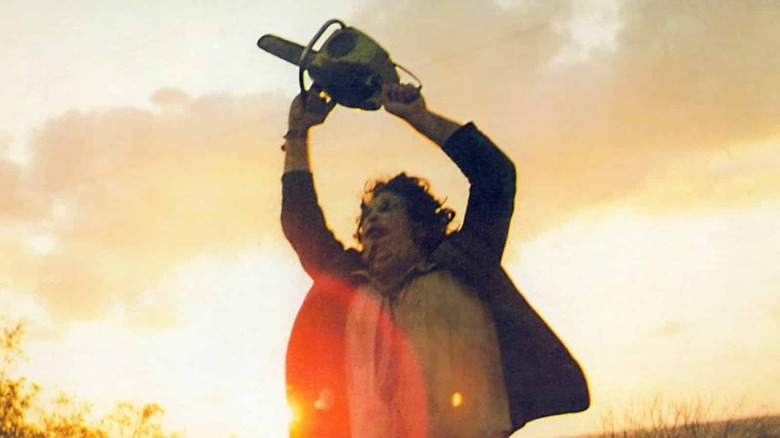 Leatherface, as seen in the original The Texas Chain Saw Massacre waving his saw above his head at magic hour.