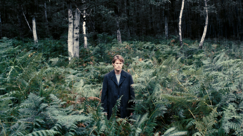 Willem Dafoe's character standing in a forest in Antichrist