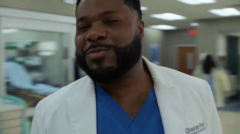 Malcolm Jamal-Warner's AJ grins while a hospital hall blurs with motion behind him in The Resident