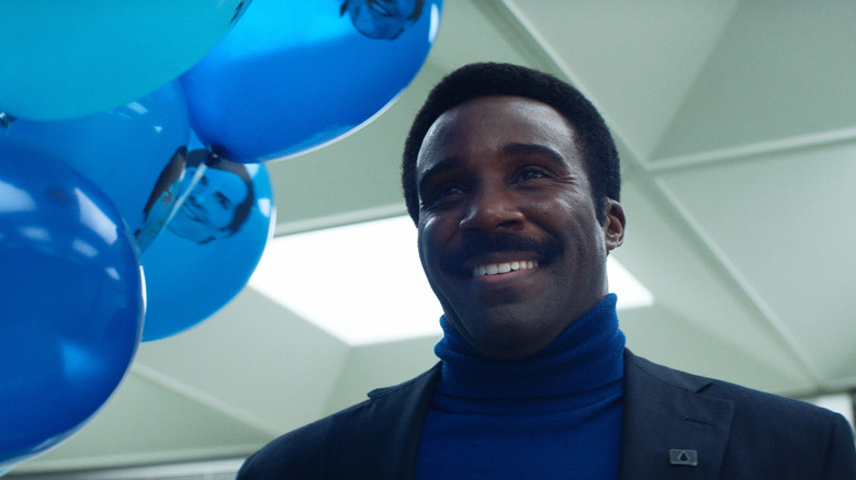 Tramell Tillman as Mr. Milchick smiling and holding a bunch of balloons in Severance