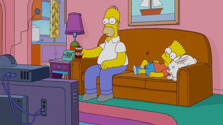 Homer and Bart on the couch watching TV. Homer is holding a beer, and Bart is resting his head on a white rabbit. From The Simsons.