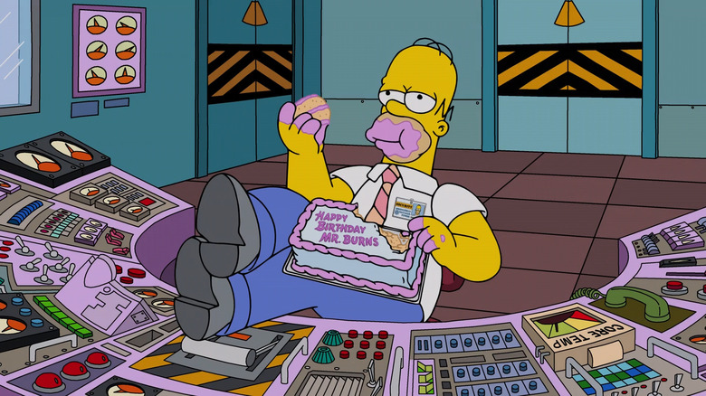 Homer eating a birthday cake for Mr. Burns at his desk in The Simpsons