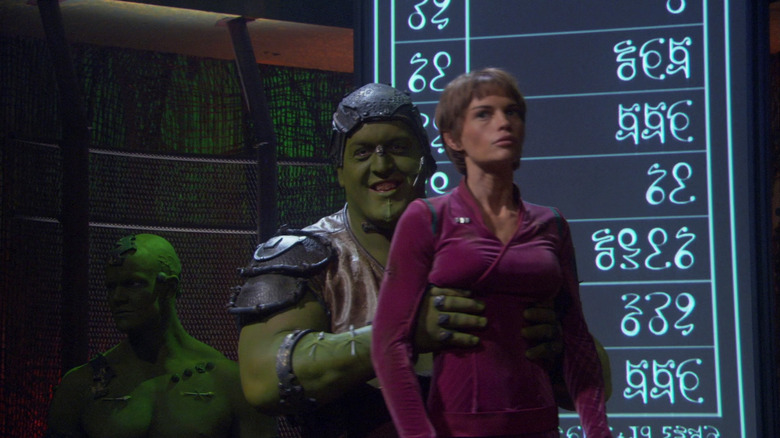 An Orion slaver, at a slave auction, holding up T'Pol for sale. A scene from Star Trek: Enrterprise.