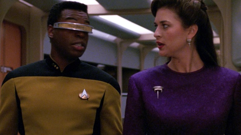 Geordi dan Dr. Brahms berjalan menyusuri koridor USS Enterprise.