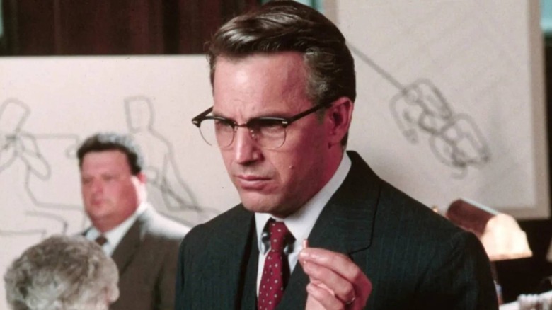 Kevin Costner como Jim Garrison sosteniendo una bala en el aeropuerto JFK