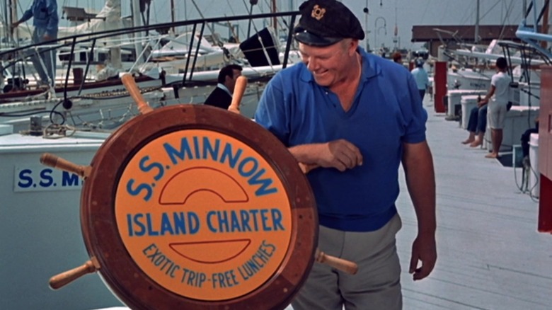 The captain standing near the SS Minnow advertising board.