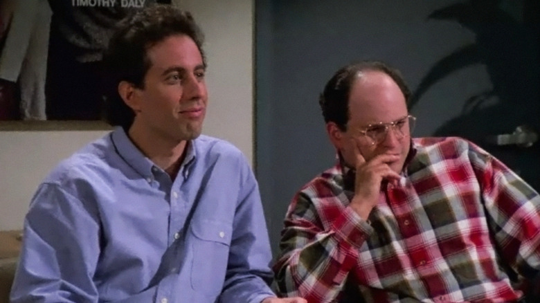 Jerry Seinfeld's Jerry, trying not to laugh, sits by Jason Alexander's George, who studies something offscreen in Seinfeld