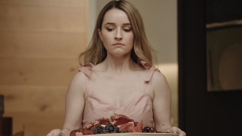 Kaitlyn Dever as Belle Gibson carrying a plate of fruit in Apple Cider Vinegar