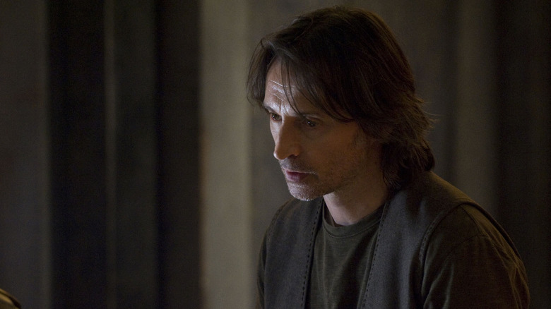 Robert Carlyle's Nicholas Rush sitting at the console looking despondent in Stargate Universe