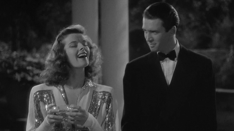 Katharine Hepburn's Tracy laughs as she stands next to James Stewart's Mike in The Philadelphia Story