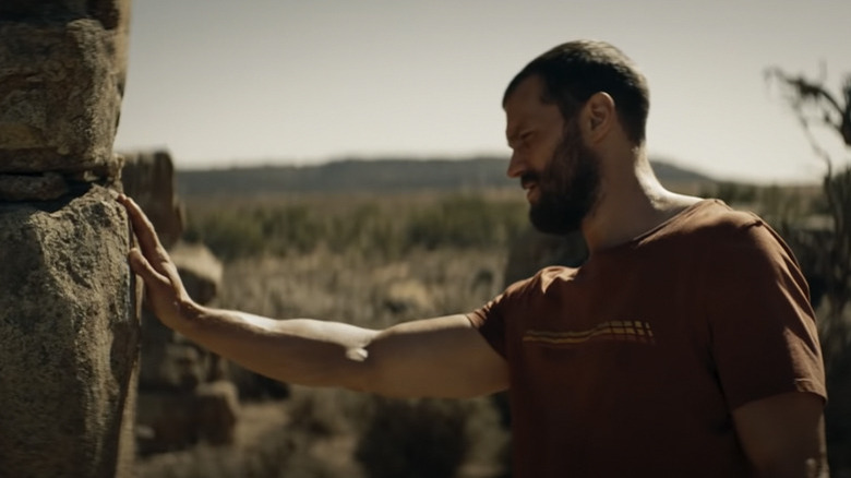 Jamie Dornan touching a rock in The Tourist