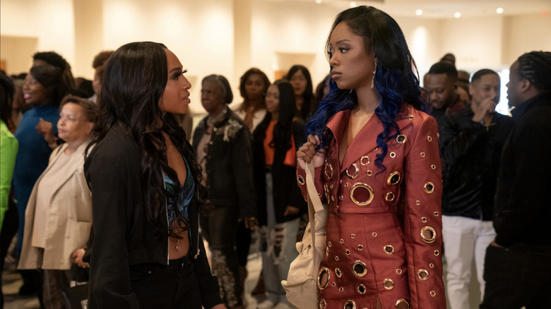 Kimmie and Reign stand next to each other among a crowd of people at an indoor event