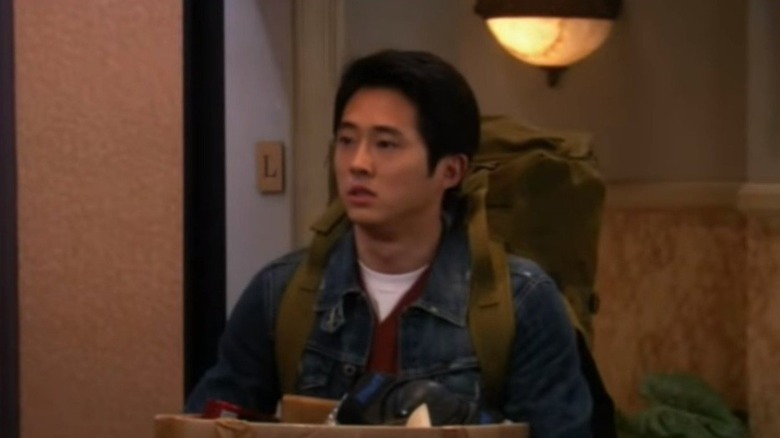 Steven Yeun como Sebastian sosteniendo una caja en The Big Bang Theory