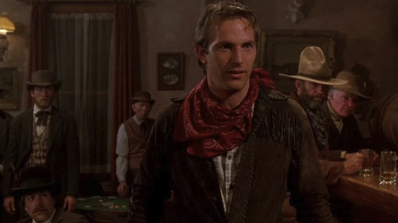 Kevin Costner as Jake in Silverado stares at someone off camera in a bar