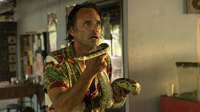 Walton Goggins como Rick Hatchett segurando uma cobra na 3ª temporada de Lotus White