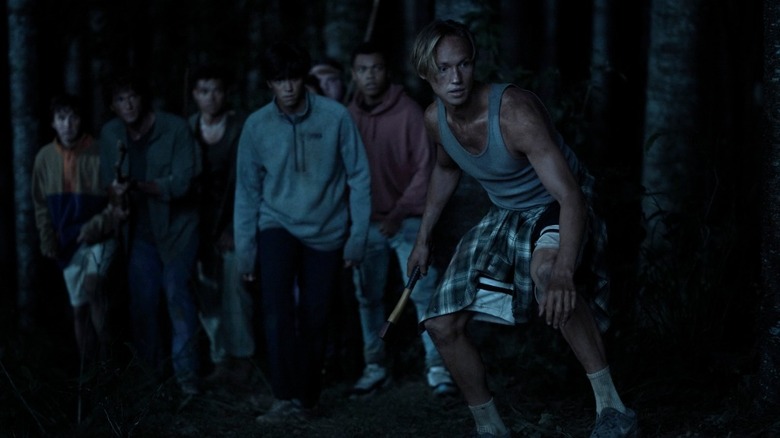 seven boys in the dark with one boy in the front crouched down with a stick in his hand