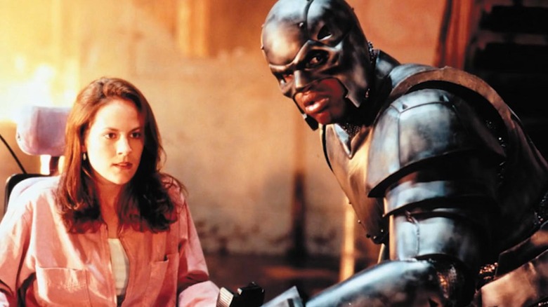 Susan sparks sitting in a wheelchair (Annabeth Fire), John Henry Irons (Shaquille O'Neal) in steel suit in steel