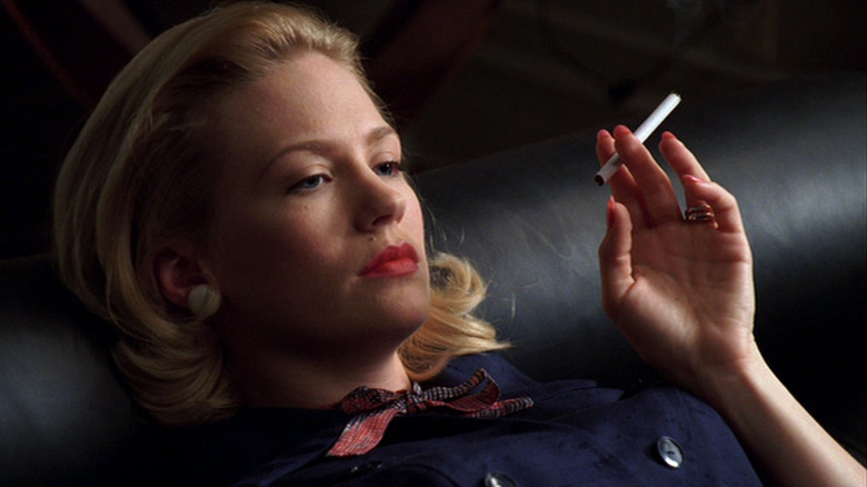 A close-up of Betty Draper looking forlorn while holding a cigarette