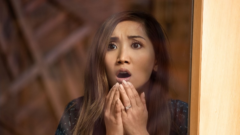 Brenda Song as Jenn staring out of a window in disbelief in Secret Obsession