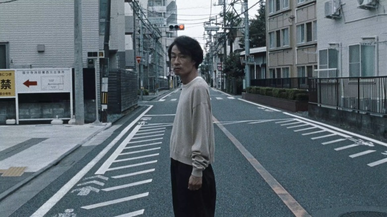 Takuji Matsuoka (Mutsuo Yoshioka) stands in the middle of the street in Chime