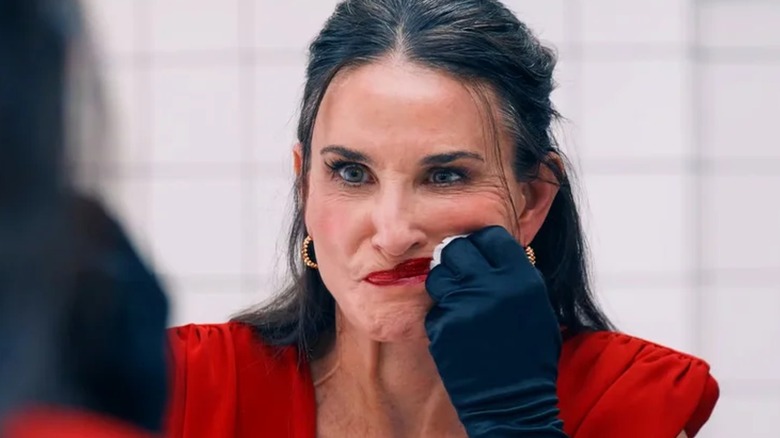 Demi Moore's Elizabeth angrily smearing her makeup in a mirror in The Substance