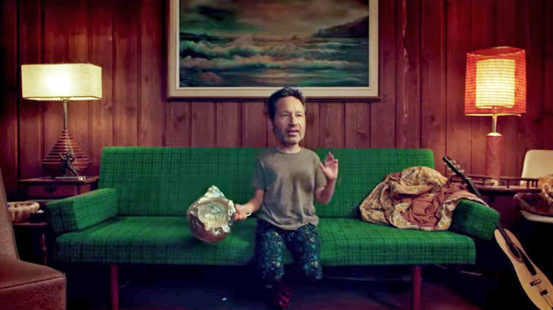 A small boy with Fox Mulder's adult head, sitting on a couch eating popcorn on The X-Files