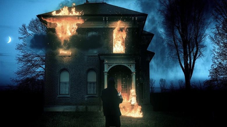 A man in a top hat standing in front of a burning building at night in "Where the Devil Roams."