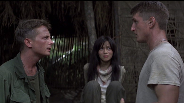 Sean Penn as Meserve and Michael J. Fox as Eriksson huddle in Casualties of War arguing in front of Thuy Thu Le as Oanh