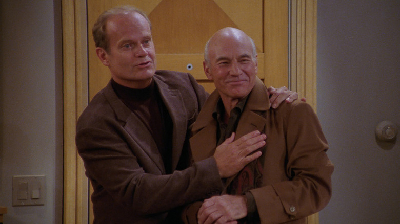 Frasier Crane and Alistair Burke, from the series "Frasier," holding each other in a friendly way.