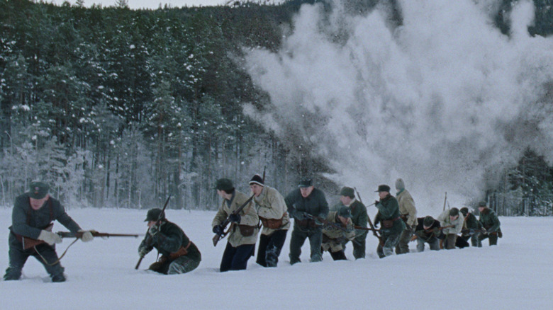 A column of soldiers making their way through the snow as an explosion goes off behind them in Number 24