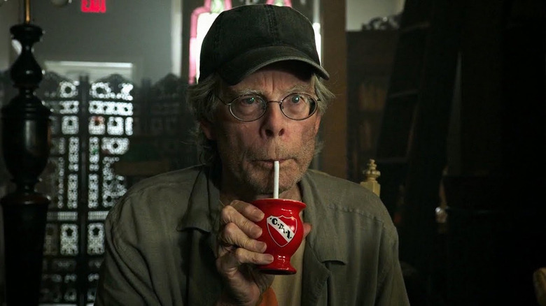 Stephen King as a show owner drinking from a tiny cup in It Chapter Two